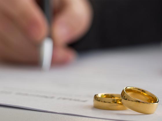 Divorce image of rings and someone signing a document